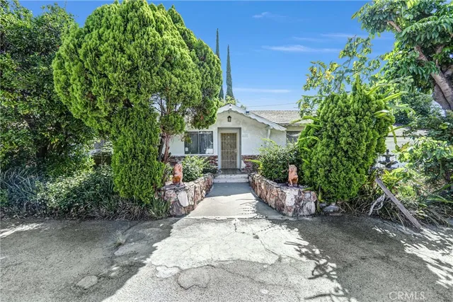 a view of a house with potted plants and large trees