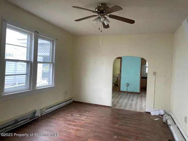 an empty room with wooden floor cabinet and windows