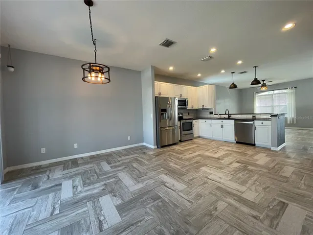 a large kitchen with granite countertop a refrigerator and a stove top oven