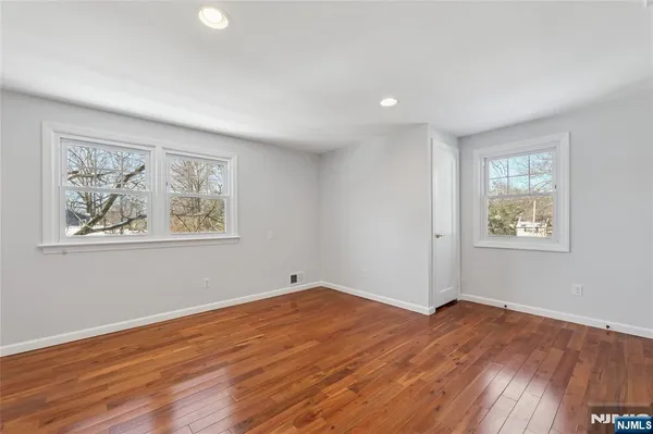 a view of empty room with wooden floor and window