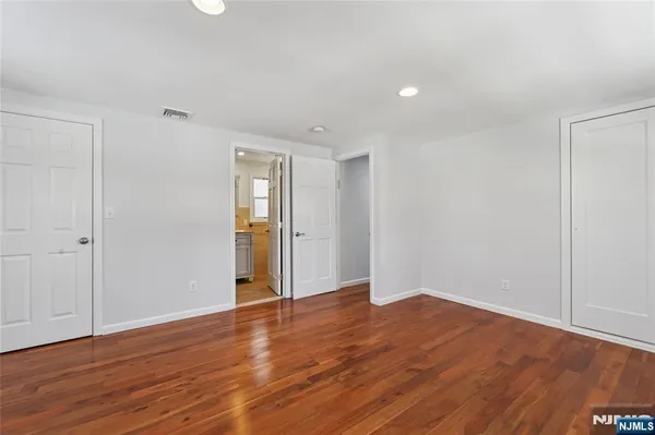 a view of an empty room with wooden floor and closet