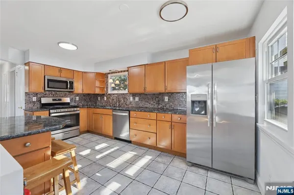 a kitchen with stainless steel appliances granite countertop a refrigerator a stove top oven and sink