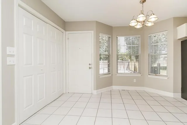 a view of an empty room with windows and chandelier