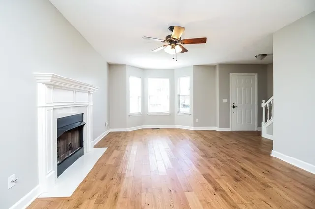 a view of an empty room with wooden floor and a fireplace