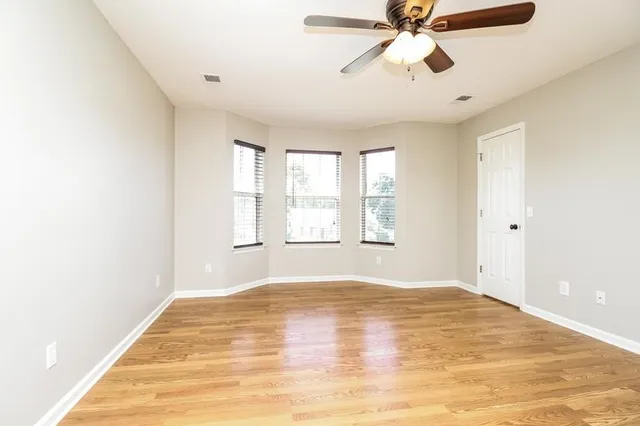 a view of an empty room with window and a chandelier fan