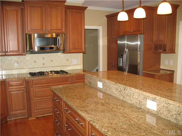 4105 John S Raboteau Wynd Raleigh, NC 27612 - Photo 7 of 20 a kitchen with granite countertop stainless steel appliances and wooden cabinets