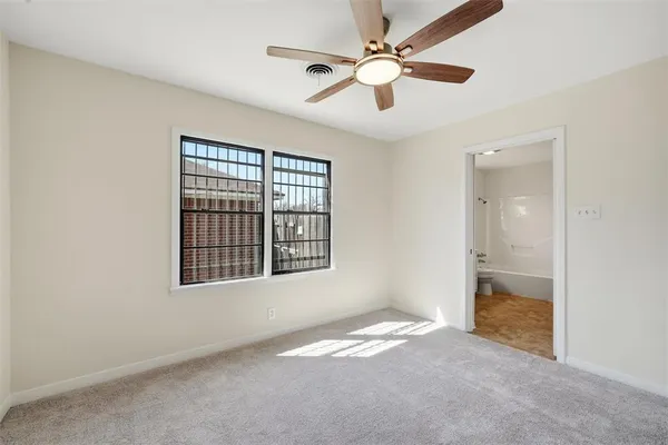 an empty room with chandelier fan and windows