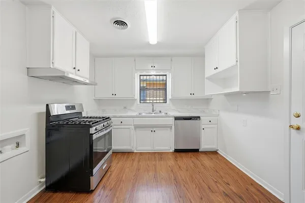 a kitchen with a white cabinets and wooden floor