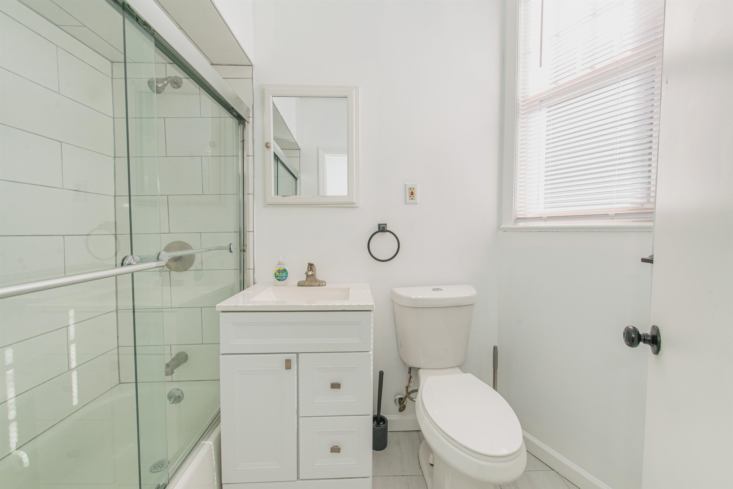 1308 27th Street, Unit 2 North Bergen, NJ 07047 - Photo 12 of 15 a bathroom with a toilet a sink a mirror and a window