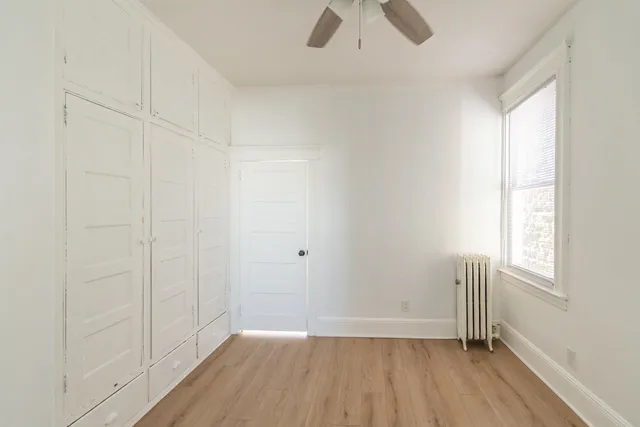 an empty room with wooden floor cabinet and windows