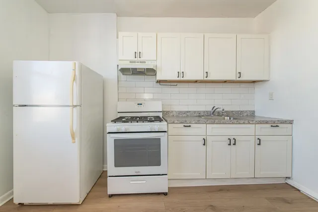a kitchen with granite countertop white cabinets and white appliances
