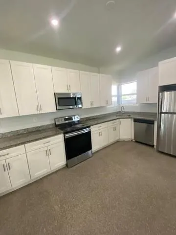 a kitchen with granite countertop white cabinets and stainless steel appliances