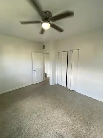 an empty room with fan and windows