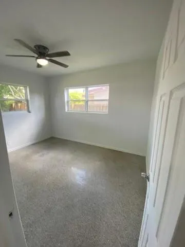 an empty room with windows and fan