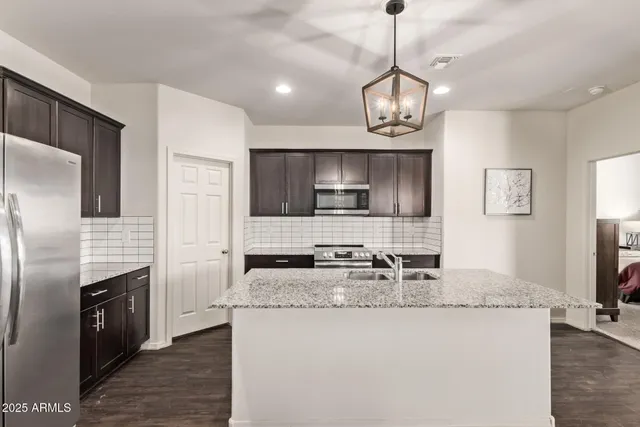 a kitchen with kitchen island granite countertop stainless steel appliances a sink stove and refrigerator