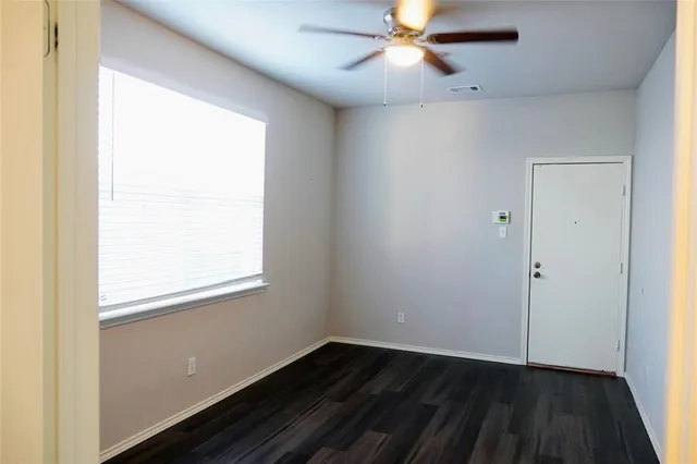 an empty room with wooden floor closet and fan