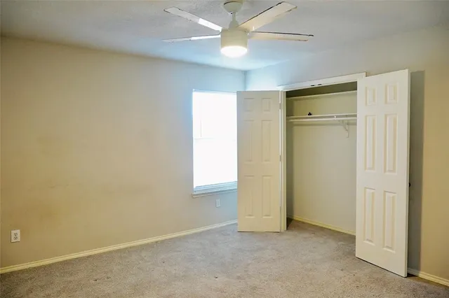 an empty room with a ceiling fan and a window