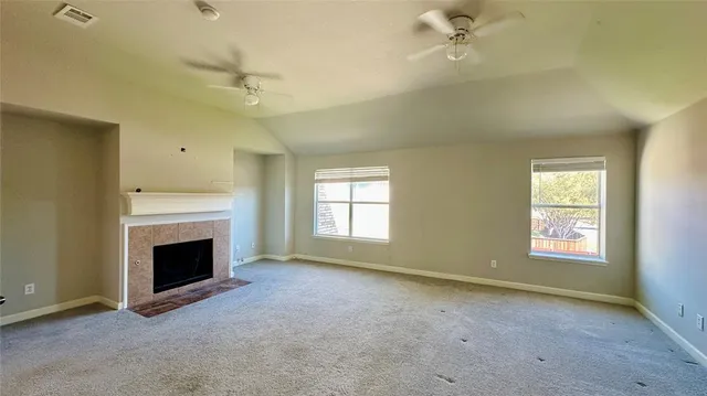 an empty room with windows and fireplace
