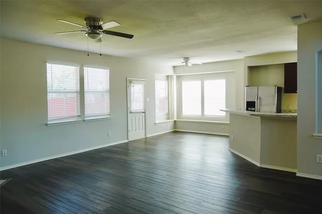 a view of an empty room with window and wooden floor