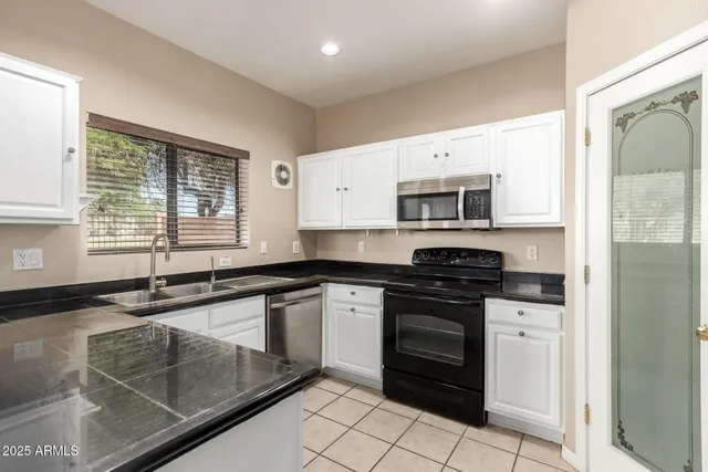 a white kitchen with granite countertop a sink and white cabinets