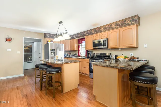 a kitchen with granite countertop a stove top oven a sink dishwasher a dining table and chairs with wooden floor