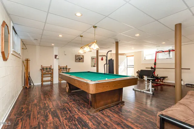 a room with wooden floor pool table and chairs