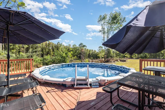a patio with wooden floor a yard a table and chairs