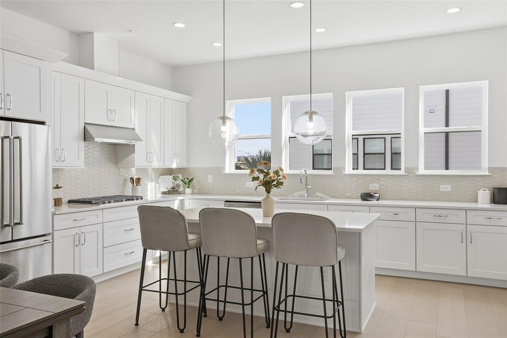 2174 Whitney Marsh Alley Orlando, FL 32804 - Photo 8 of 50 a kitchen with stainless steel appliances granite countertop a sink a stove a refrigerator and white cabinets with wooden floor