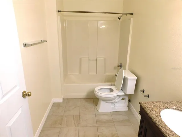 a bathroom with a granite countertop bathtub shower and toilet
