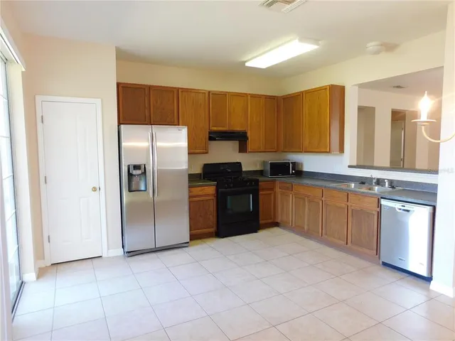 a kitchen with stainless steel appliances granite countertop a stove a sink dishwasher a refrigerator and cabinets with wooden floor