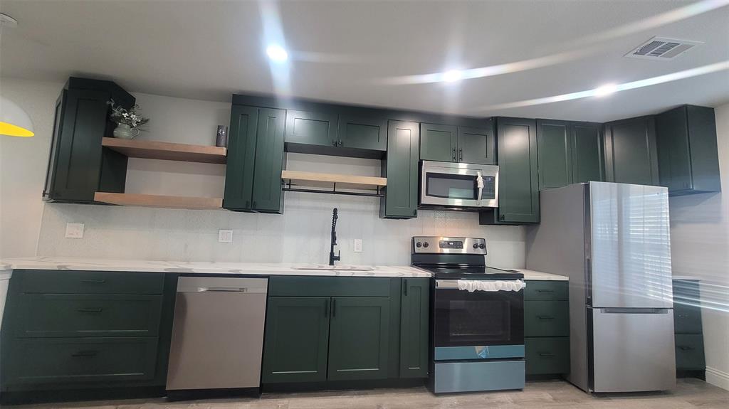 1204 Live Oak Street Commerce, TX 75428 - Photo 3 of 14 a kitchen with stainless steel appliances a refrigerator a stove a microwave a sink and dishwasher