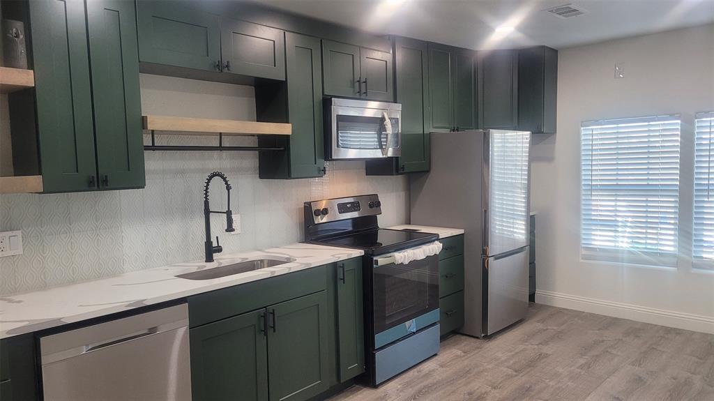 1204 Live Oak Street Commerce, TX 75428 - Photo 9 of 14 a kitchen with stainless steel appliances granite countertop a sink stove and refrigerator
