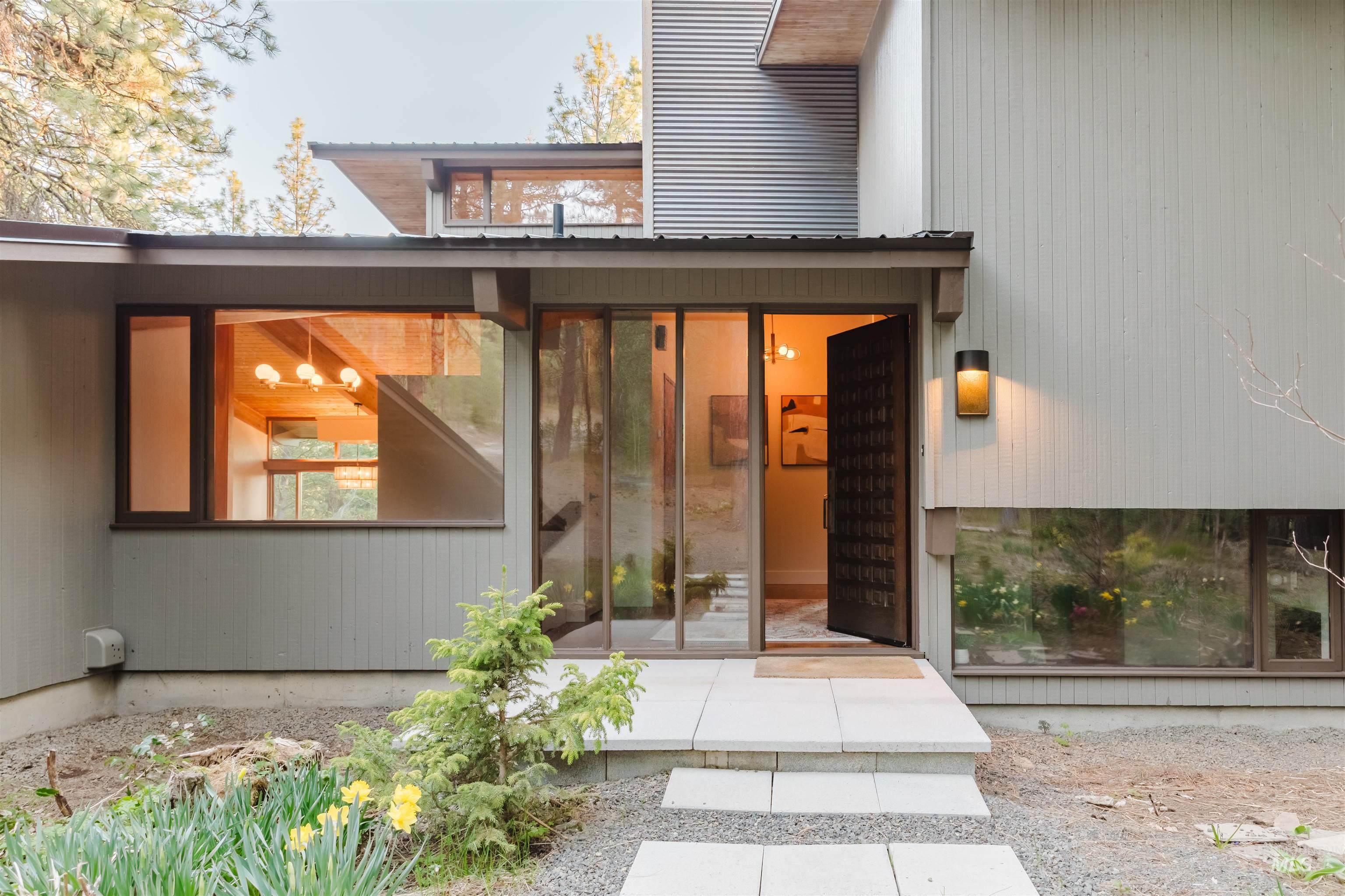 136 Silver Fox Trail McCall, ID 83638 - Photo 2 of 31 Modern architectural exterior featuring a textured wooden entry door, expansive glass window panels, and a tiered concrete walkway