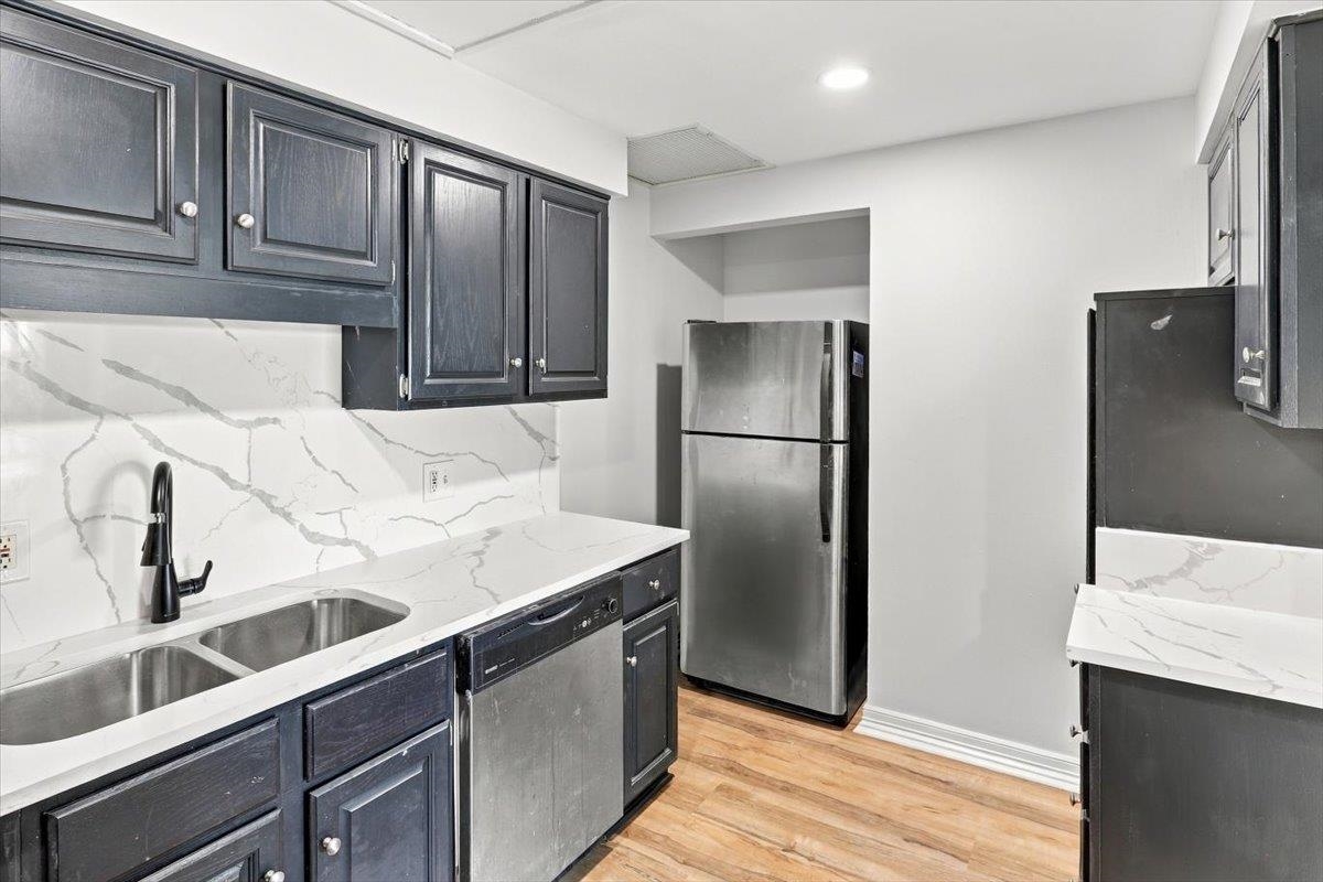 655 Riverside Drive, Unit 608B Memphis, TN 38103 - Photo 10 of 28 Kitchen featuring dark-finished cabinetry, stainless steel appliances, a double basin sink, and wood-finish flooring