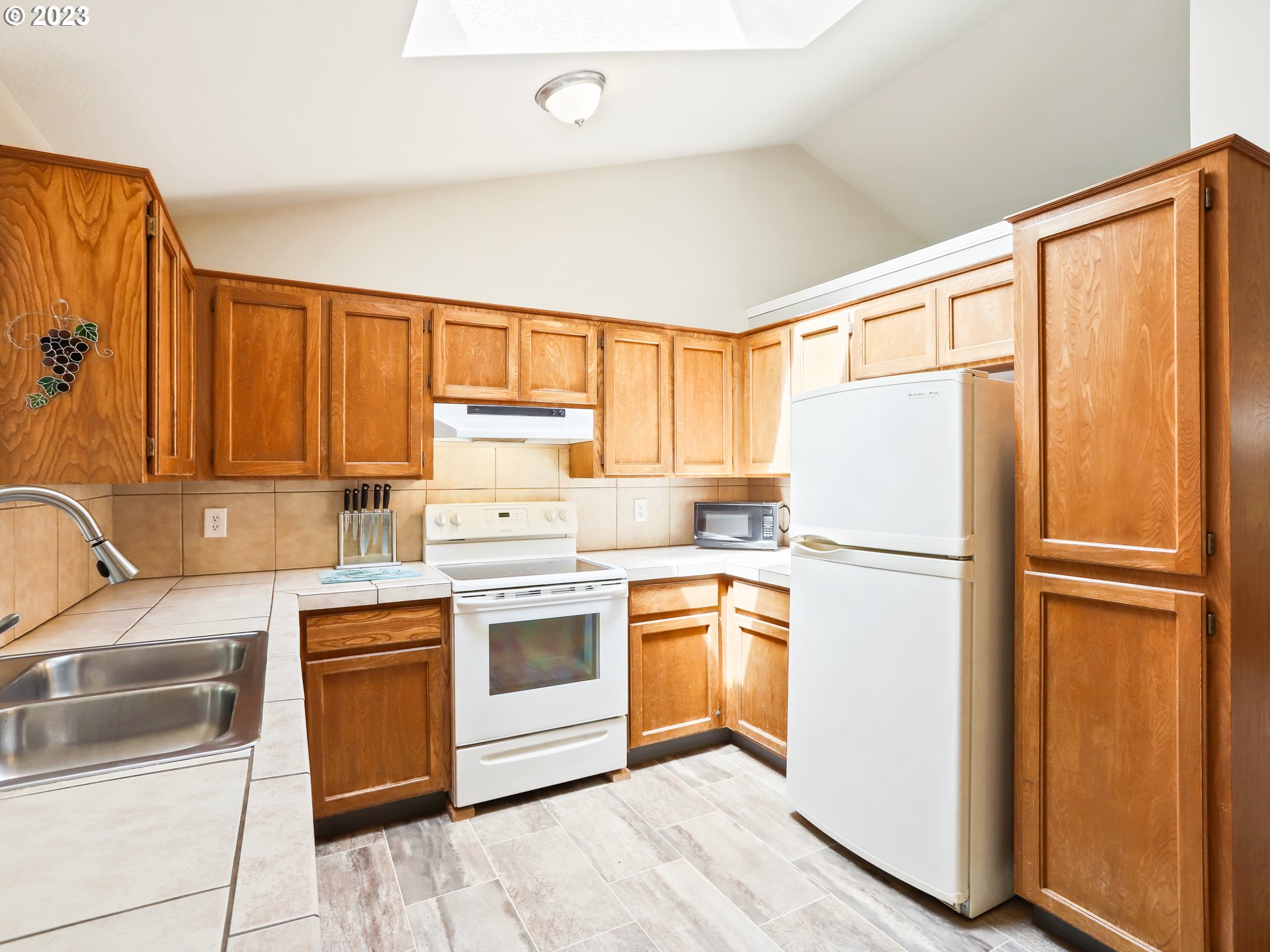 13224 Southwest Shore Drive Portland, OR 97223 - Photo 4 of 30 a kitchen with a refrigerator sink stove and cabinets