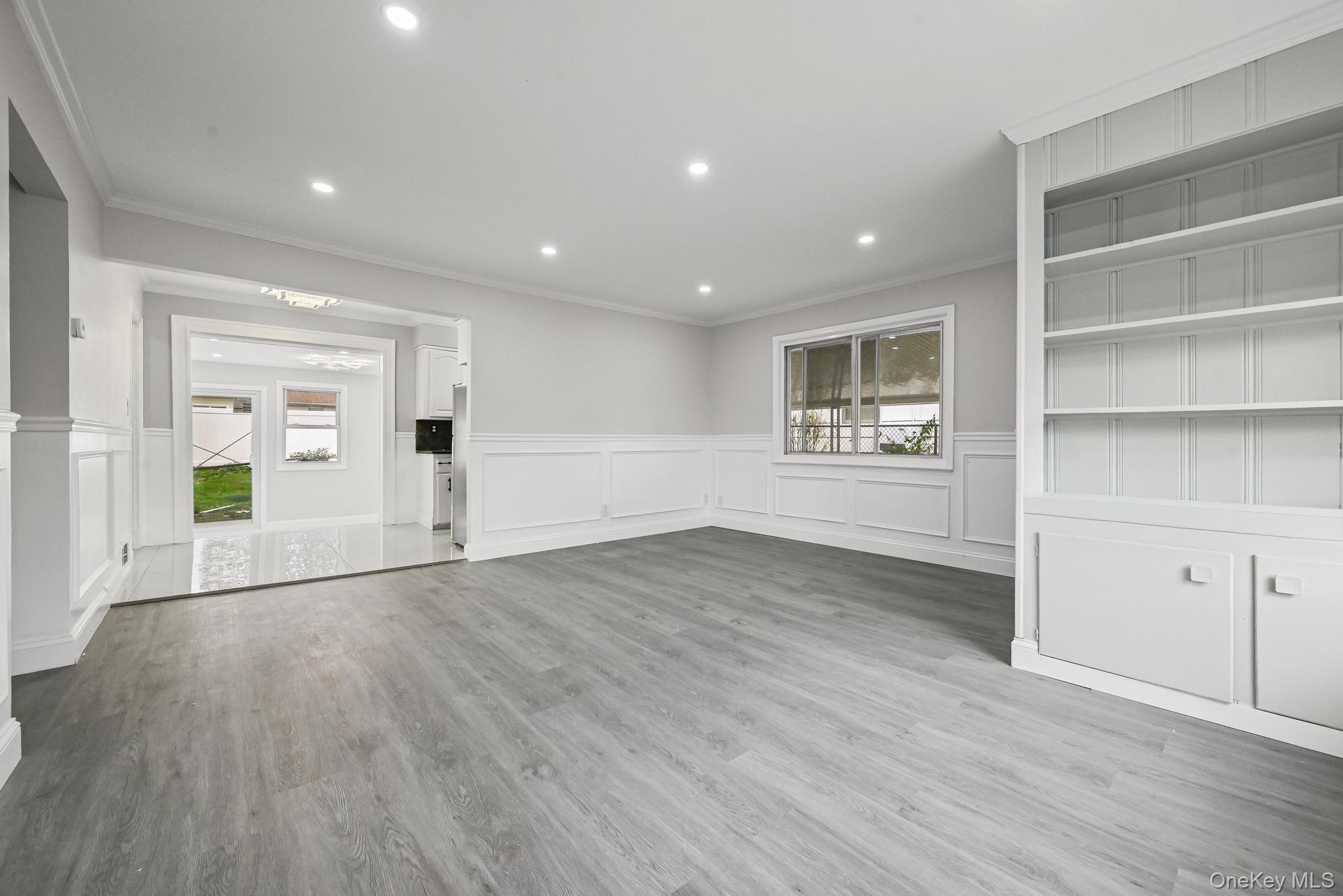 312 Coventry Road South West Hempstead, NY 11552 - Photo 13 of 30 Unfurnished living room with healthy amount of natural light, a decorative wall, a wainscoted wall, light wood-type flooring, and recessed lighting