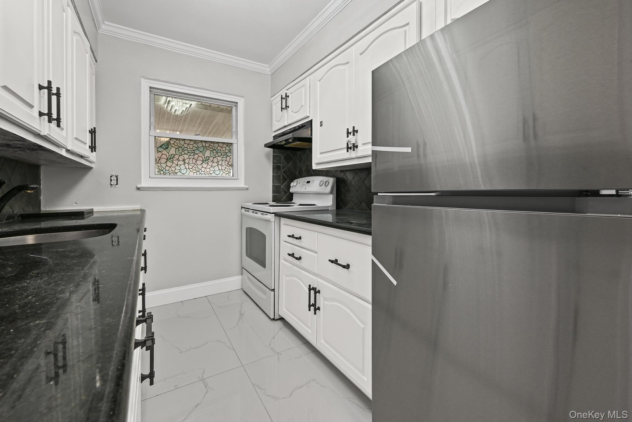 312 Coventry Road South West Hempstead, NY 11552 - Photo 19 of 30 Kitchen featuring freestanding refrigerator, electric range, ornamental molding, light marble finish flooring, and white cabinets