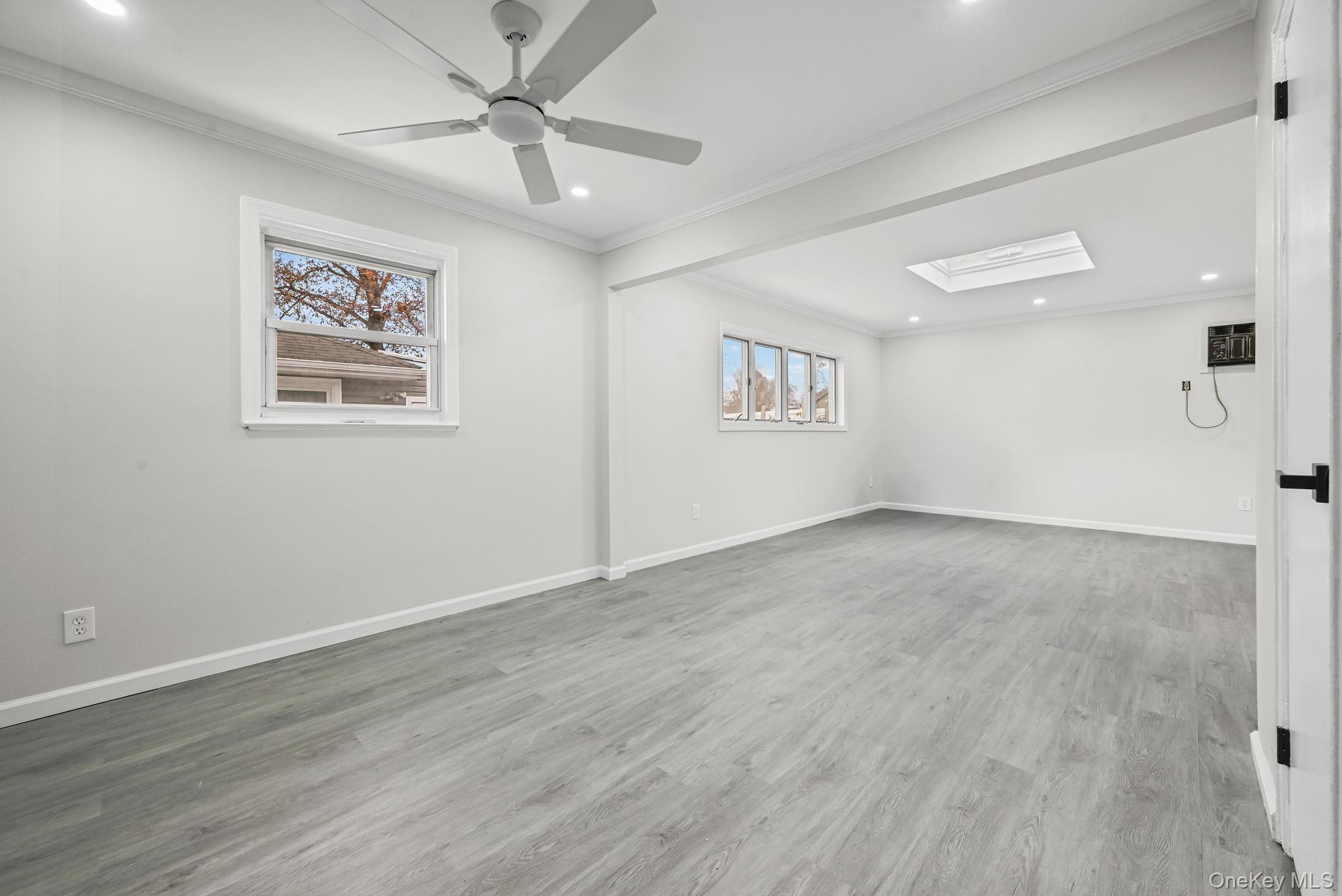 312 Coventry Road South West Hempstead, NY 11552 - Photo 21 of 30 Empty room with ornamental molding, a skylight, light wood finished floors, recessed lighting, and ceiling fan