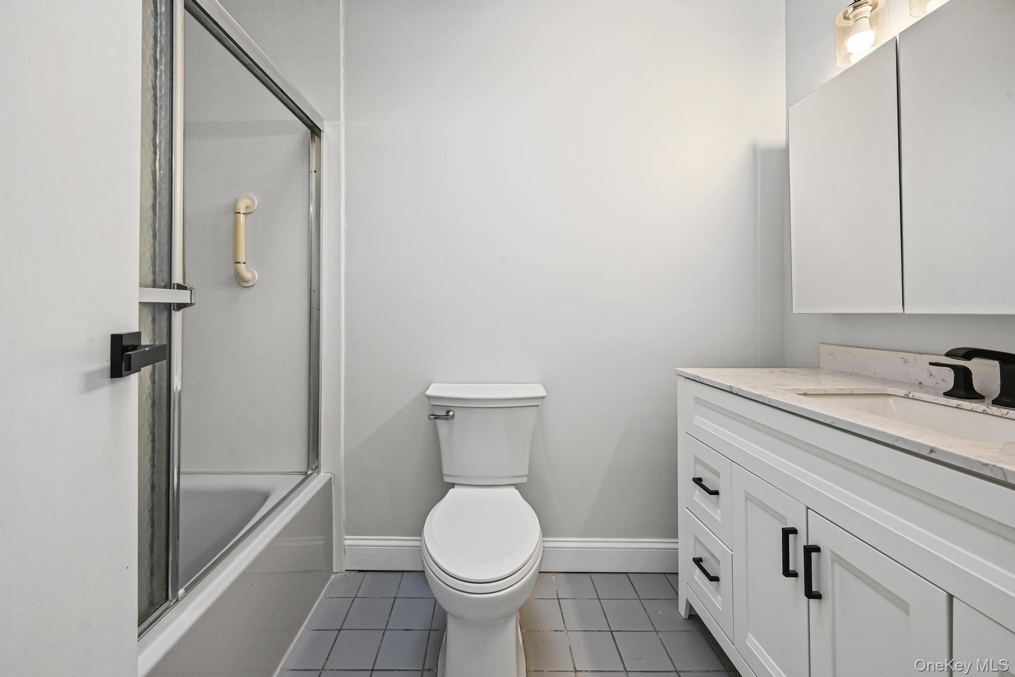 312 Coventry Road South West Hempstead, NY 11552 - Photo 23 of 30 Full bath with dark tile patterned flooring, vanity, and shower / bath combination with glass door