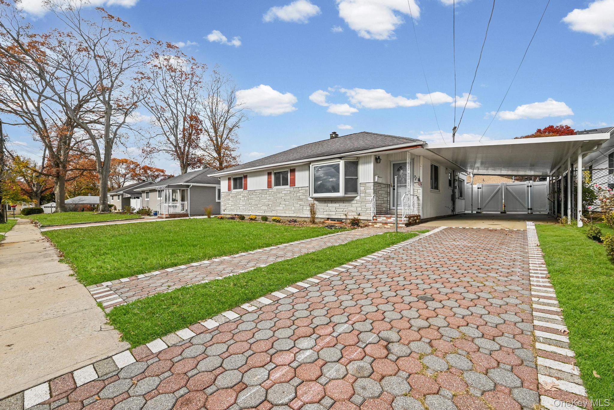 312 Coventry Road South West Hempstead, NY 11552 - Photo 3 of 30 View of front of home featuring a carport, a front lawn, decorative driveway, stone siding, and a gate
