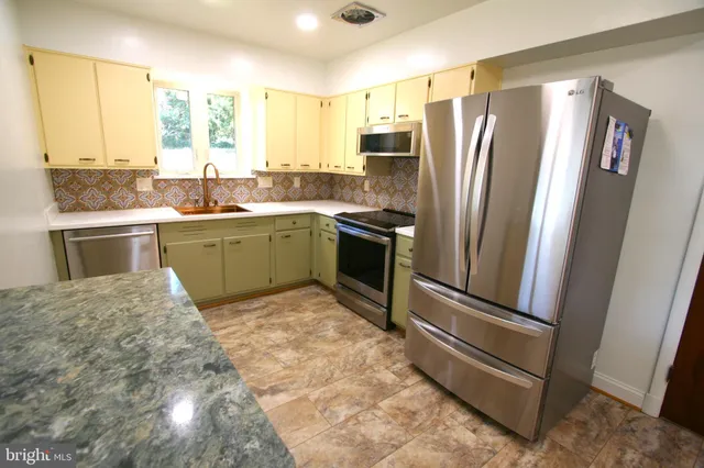 a kitchen with stainless steel appliances granite countertop a refrigerator and a stove