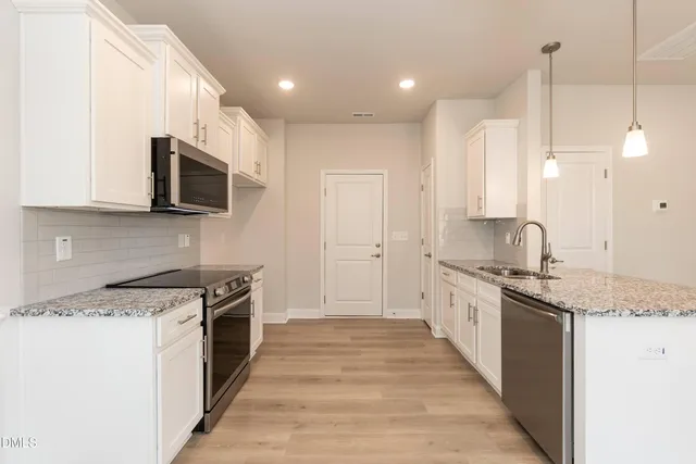 a large kitchen with kitchen island granite countertop a sink and stainless steel appliances