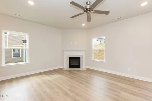 a view of an empty room with wooden floor and a kitchen