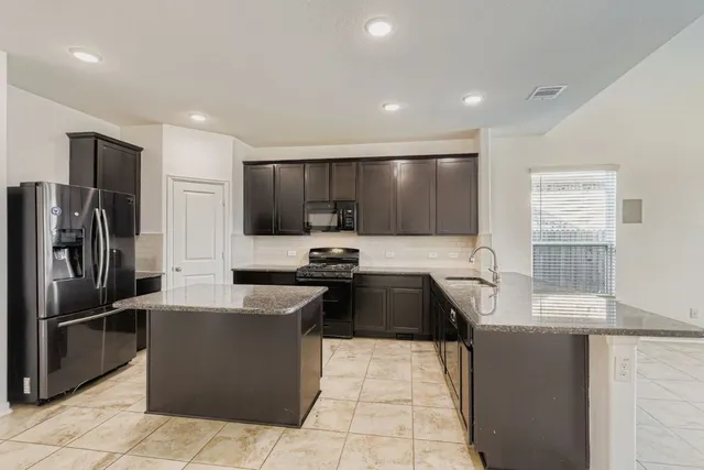 a kitchen with granite countertop a refrigerator and a stove top oven