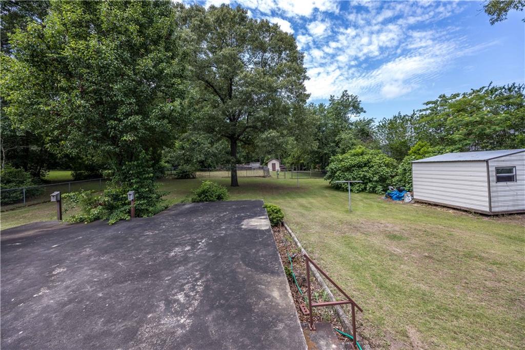 View of yard with a storage unit, an outdoor structure, and view of wooded area