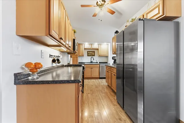 a kitchen with stainless steel appliances granite countertop a refrigerator a sink and a stove