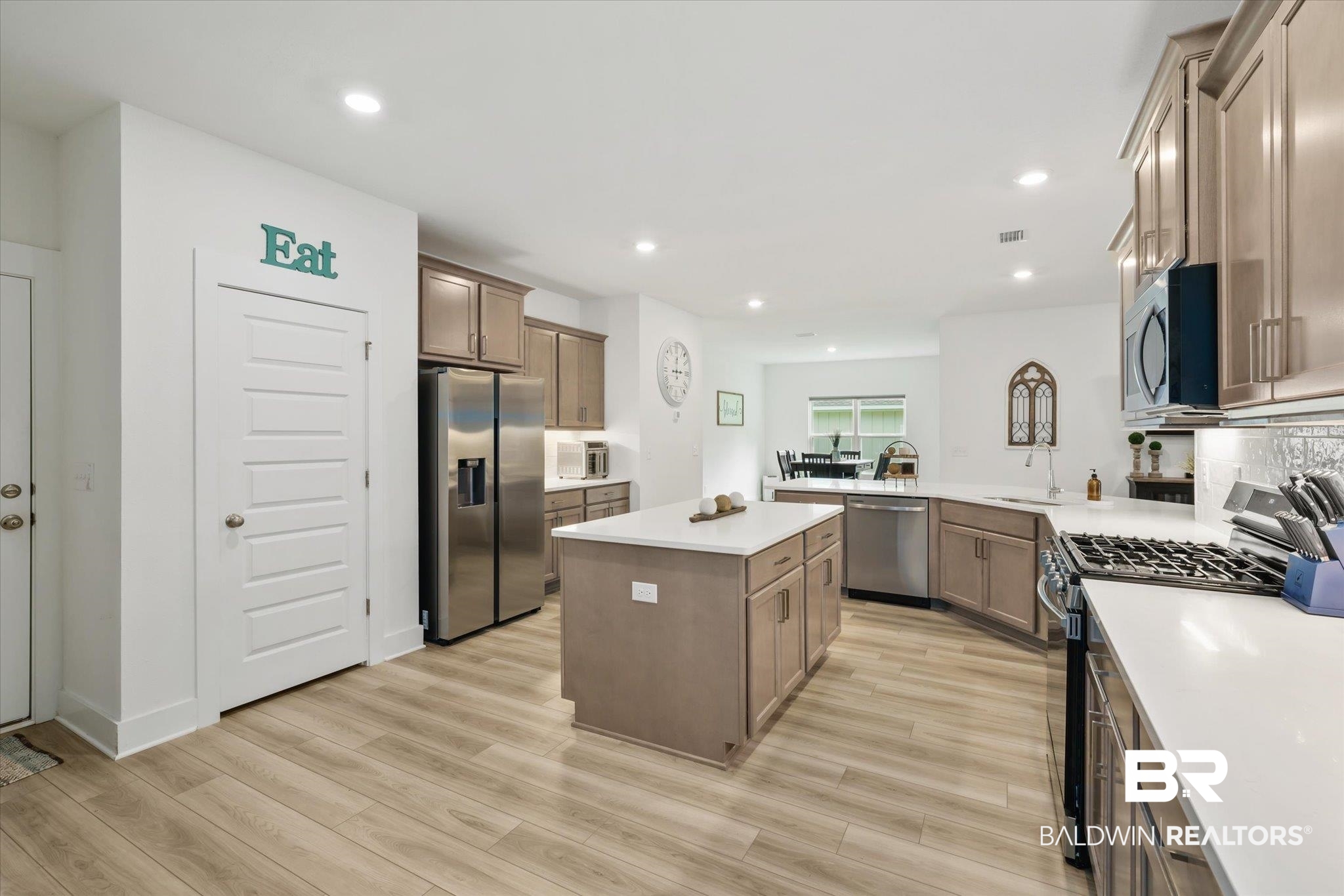 263 Bronze Street Fairhope, AL 36532 - Photo 10 of 47 Kitchen with light wood-type flooring, tasteful backsplash, stainless steel appliances, kitchen peninsula, and a center island