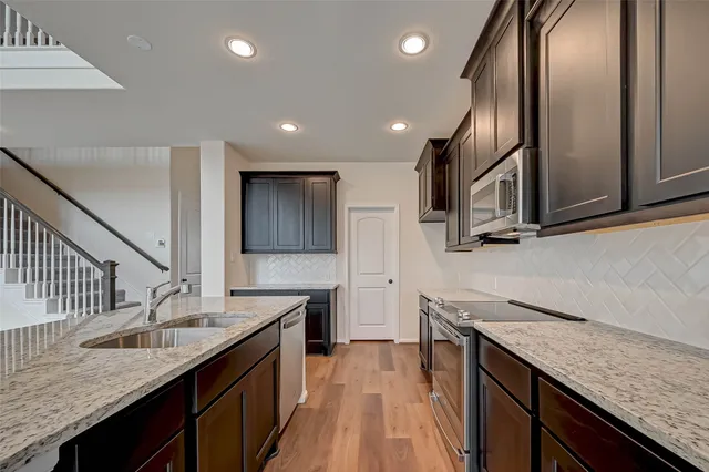 a kitchen with granite countertop kitchen island stainless steel appliances a sink stove top oven and refrigerator