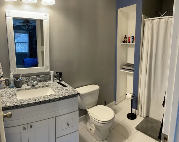 a bathroom with a granite countertop toilet and a sink