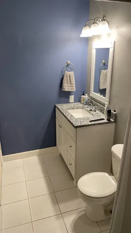 a bathroom with a granite countertop toilet a sink and a mirror